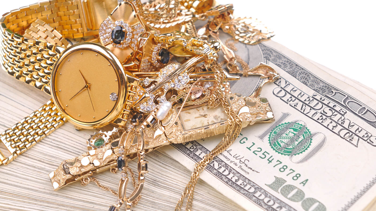 pile of gold jewelry on top of cash